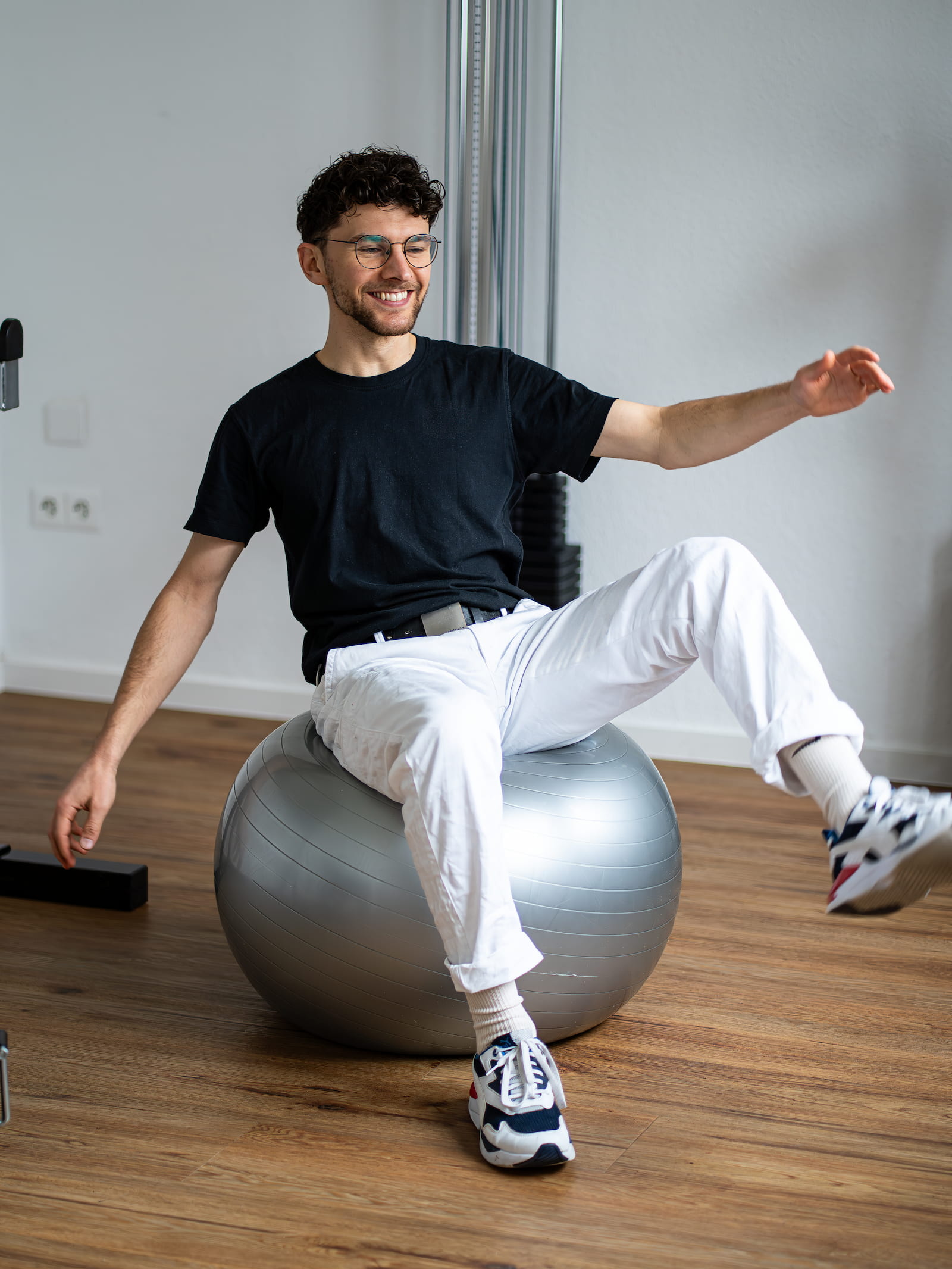 Jonas Ferenc Kohlhage sitzt auf einem grauen Pezziball und balanciert mit einem Bein ausgestreckt.